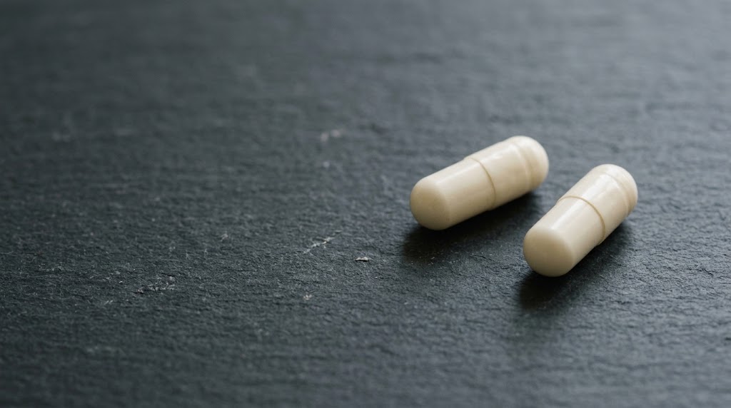 Two white capsules on a dark textured surface