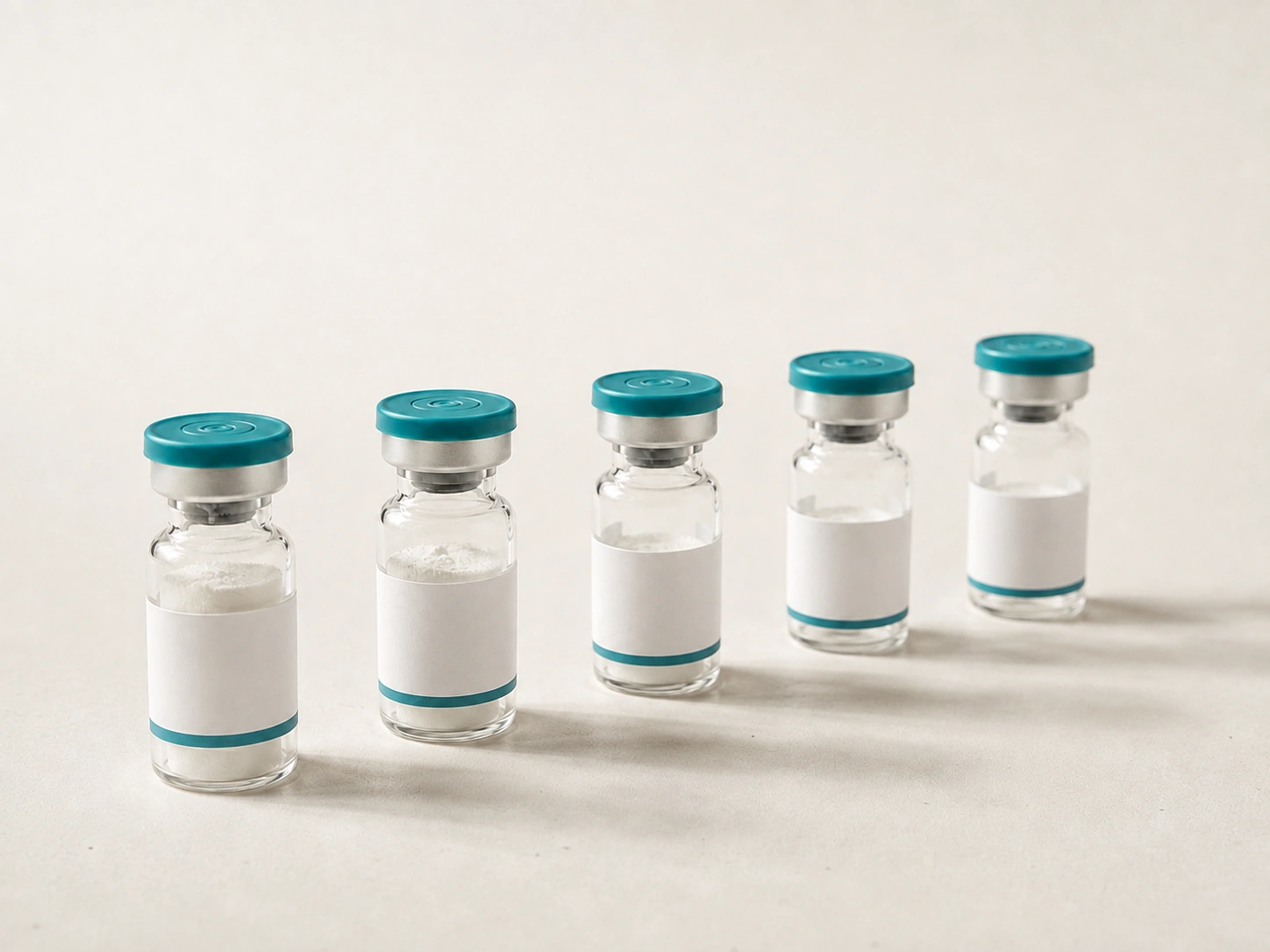 Five identical unlabelled peptide vials with teal caps arranged in a row on a pale surface